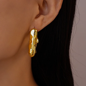 Detail of molten style gold earrings featuring a liquid texture on model ear