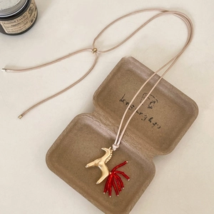 Detail of golden horse pendant with red bead tassels on an adjustable brown cord necklace