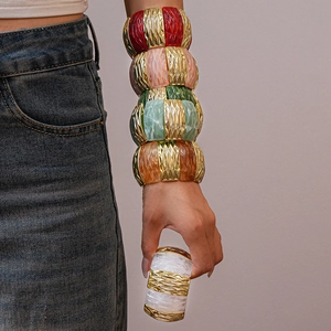 Close-up of stacked acrylic resin bracelets with colorful marble textures and gold metal