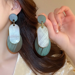 Detail of green resin vintage style hoop earrings on a model with geometric layers