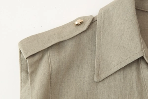 Close-up of khaki linen dress shoulder featuring epaulet design and golden button detail