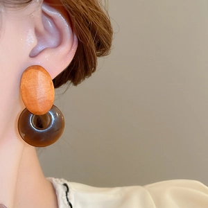 Detailed close-up of geometric resin drop earrings featuring wood and resin elements