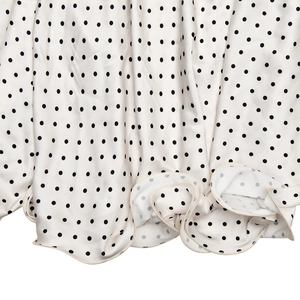 Détail de l'ourlet de la robe en satin blanc à pois noirs avec bord élégant à volants