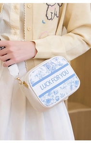 Detail of white camera bag with blue floral print and LUCK FOR YOU text on wide strap