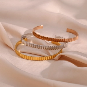 Detailed close-up of textured vertical stripe bangles in gold, silver, and rose gold