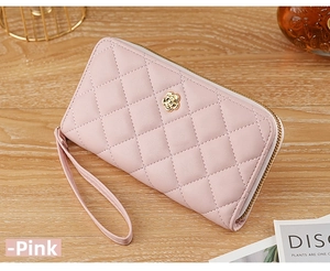 Pink quilted leather wristlet wallet with gold flower buckle on wooden table