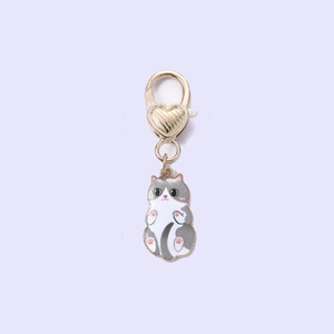 Detail of a gold heart lobster clasp with a grey and white enamel cat charm