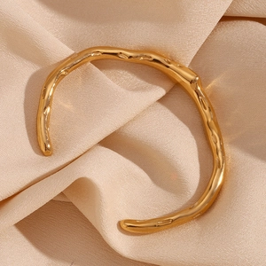 Detailed view of 18K gold plated irregular wavy cuff bracelet on soft silk background