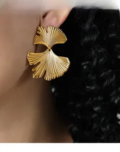Close-up of elegant gold ginkgo leaf earrings with detailed veins on a model