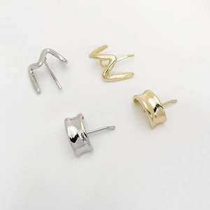 Detail of minimalist wave and shield-shaped metal hair clips in gold and silver finish