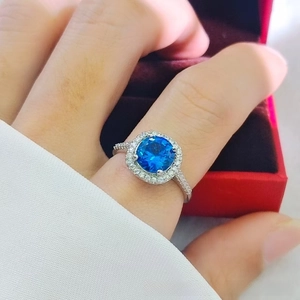 Macro shot of a silver ring featuring a blue gemstone center and halo diamond setting