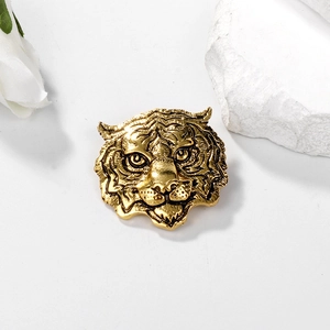 Vintage golden tiger head brooch featuring intricate embossed textures on white background