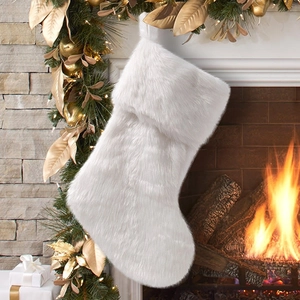 White faux fur Christmas stocking hanging on a festive mantel with warm glowing lights