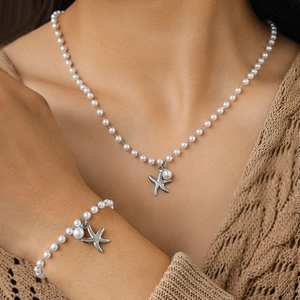 Close-up of pearl necklace and bracelet set featuring a silver starfish pendant on model