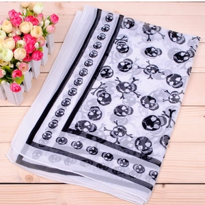 Detail of white chiffon pirate skull scarf with black edge stripes on wood background