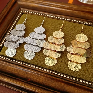 Detail of layered gold and silver leaf-shaped tassel earrings in a vintage frame