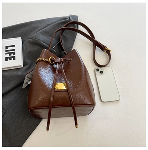 Détail du sac seau marron en cuir grainé avec cordon de serrage et logo en métal doré