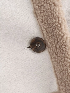 Detailed close-up of beige fleece fabric texture with dark brown button on the jacket