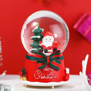 Close-up of a Christmas snow globe with Santa and a tree on a red Merry Christmas base
