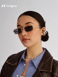 Detalle de gafas de sol cuadradas de metal con lentes oscuras y bisagras ornamentadas