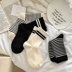 Flat lay of knit wool blend crew socks in black, white, and striped patterns on soft fabric