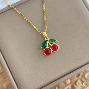 Elegant cherry pendant necklace with red crystals and green leaves on a thin gold chain