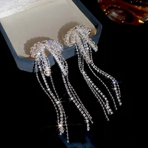 Elegant silver bow earrings with zircon tassels and sparkling stones on jewelry box