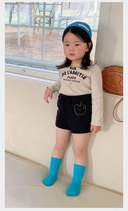 Girl wearing beige long sleeve shirt and blue knit shorts with matching socks