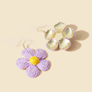 Macro detail of hand-woven raffia flower earrings in purple and yellow with gold hooks