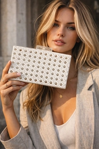 Detail of white hollow woven clutch bag with acrylic clasp and elegant hard shell texture