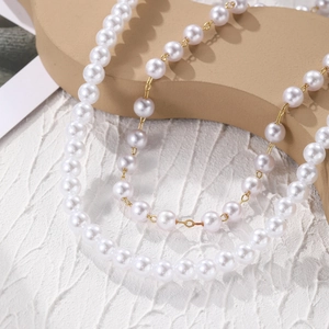 Detailed macro view of white baroque pearls with golden metal clasp on a textured surface