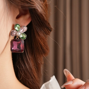 Close-up of vintage floral square earrings with crystals and pearl on a model