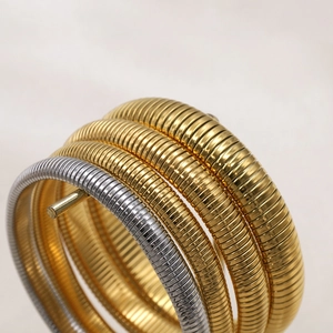 Detailaufnahme elastischer Schlangenknochen-Armbänder in Gold und Silber mit Spiralstruktur