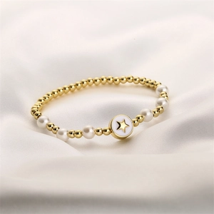 Detalle de pulsera de cuentas con esferas de metal dorado, perlas blancas y dije de estrella