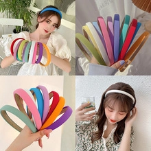 Dettagli di cerchietti sottili color macaron indossati da una modella e in mano