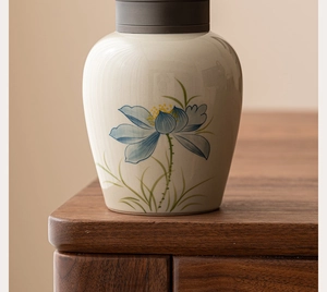Close-up of hand-painted blue lotus on cream ceramic tea canister with grey lid
