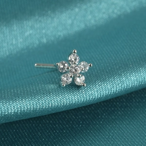 Macro shot of silver flower nose stud with clear zircon on turquoise silk background