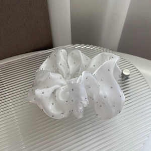 Detail of white satin scrunchie with silver rhinestone embellishments on textured base