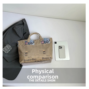 Flat lay of large newspaper print bucket bag with office essentials on white background