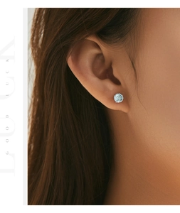 Macro shot of a round light blue gemstone stud earring on an ear lobe with silver setting