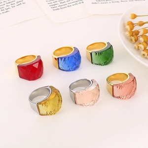 Flat lay of colorful faceted glass crystal rings on vintage book pages with dried flowers