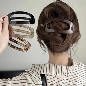 Detail view of oval cutout hair clips in black, amber, and leopard print acetate finish