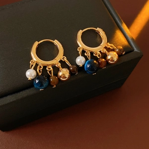 Close-up of vintage pearl and tiger eye beaded tassel hoop earrings on a black jewelry box