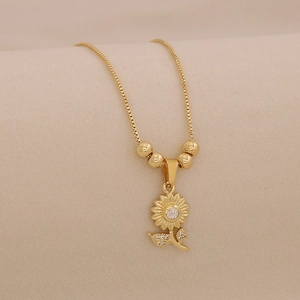 Macro view of gold sunflower pendant with sparkling cubic zirconia on a box chain necklace