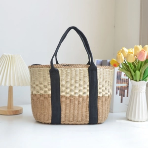 Minimalist straw woven tote bag with dual-tone design and black canvas handles