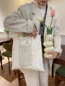 French vintage lace tote bag with embroidered pocket shown in a lifestyle cafe setting
