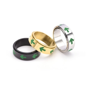 Close-up of three rotating stainless steel arrow rings in black, gold, and silver finishes