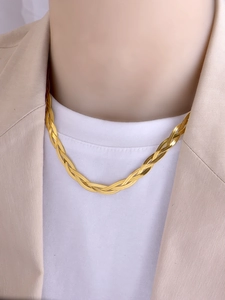 Close-up of gold layered braided snake chain necklace styled with a beige blazer
