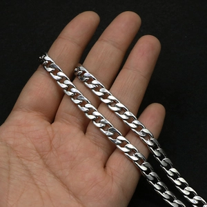 Close-up shot of a silver stainless steel Cuban link chain held in hand on black background