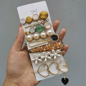 Detailed close-up of a hair clip set with faux pearls, rhinestones and daisy designs